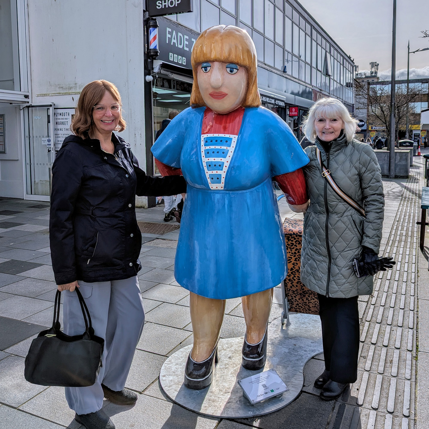 Two women standing with the Beryl Cook shopper sculpture
