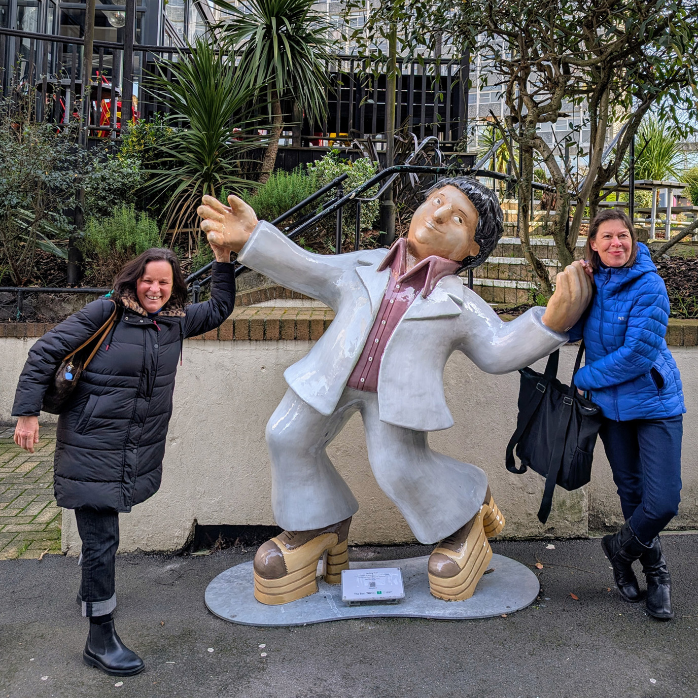 Two women stand with the Beryl Cook dancer sculpture
